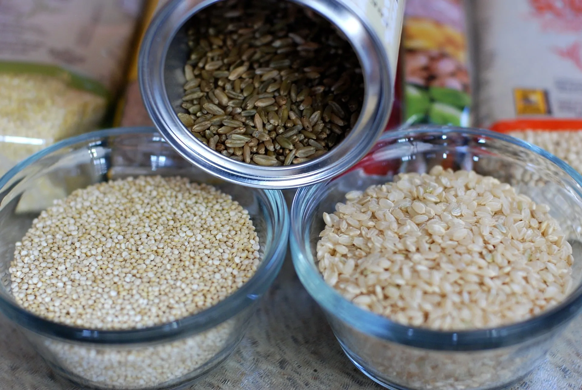 Bowls of assorted whole grains on a wooden table